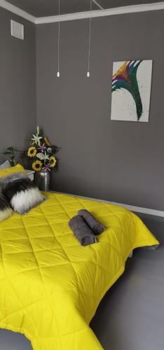 a bed with a yellow comforter in a bedroom at Blue Laoon Luxury Accommodation in Kingsburgh
