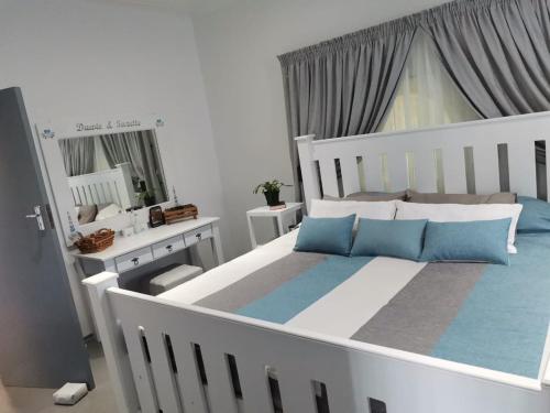 a bedroom with a large white bed with blue pillows at Blue Laoon Luxury Accommodation in Kingsburgh