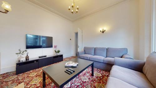 a living room with a couch and a tv at Cheerful 4 Bedroom Victorian house with back courtyard in London