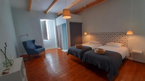 a bedroom with two beds and a blue chair at A Casa do Tenente in Faro