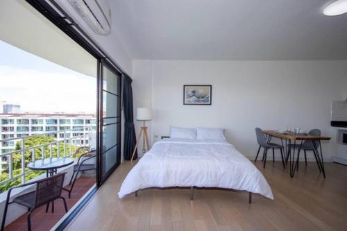 a bedroom with a bed and a balcony with a table at Modern condo in Nimman with panoramic city view in Chiang Mai