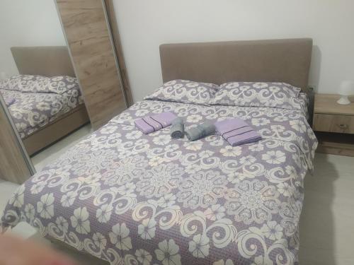 Cama con sábanas y almohadas de color púrpura y blanco en Apartman AD, en Soko Banja