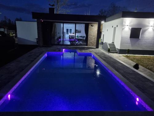 a swimming pool with purple lights in a backyard at night at Vikendica na Drini - Drinska priča in Loznica