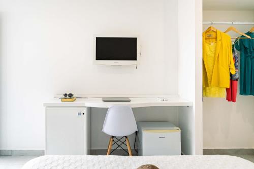 a bedroom with a white desk with a tv on a wall at Hotel & Spa Relais Freedom Club in Massa Lubrense