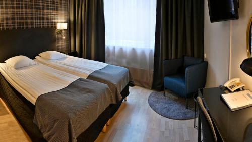 a hotel room with a bed and a blue chair at Hotel Amadeus in Halmstad