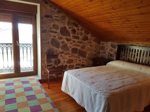 1 dormitorio con cama y pared de piedra en Casa Andrés Quilmas, en Carnota