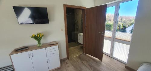 a living room with a television on the wall and a room with a window at Zajazd Stronie in Stronie Śląskie