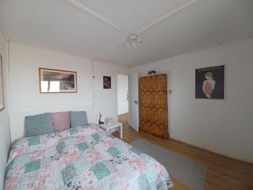 a bedroom with a bed and a wooden door at Páratlan Panoráma Kisház in Tahitótfalu