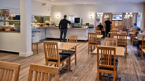 un hombre de pie en un restaurante con mesas y sillas en Hotel Amadeus, en Halmstad