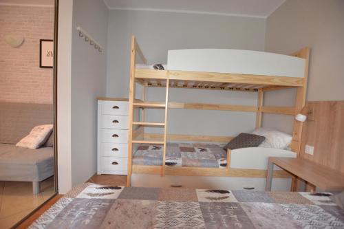 a bedroom with two bunk beds and a desk at Apartamenty Poddąbie z ogródkiem in Poddąbie