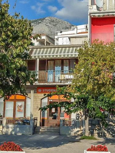 a building on a street with a mountain in the background at Apartman Melis in Podgora