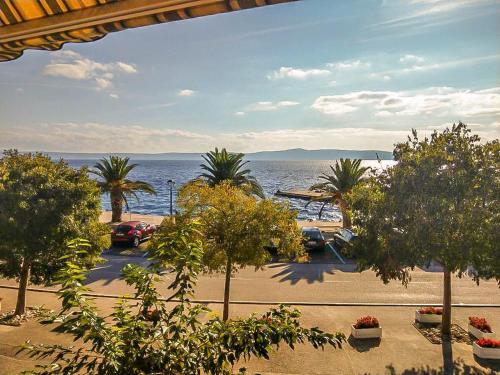 een uitzicht op een parkeerplaats met bomen en de oceaan bij Apartman Melis in Podgora