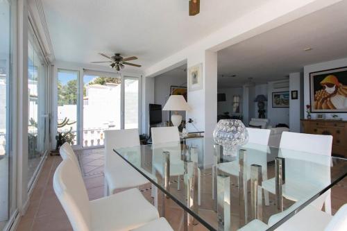 ein Esszimmer mit einem Glastisch und weißen Stühlen in der Unterkunft VILLA ALTEA HILLS, vue mer, piscine chauffée, WIFI in Alicante