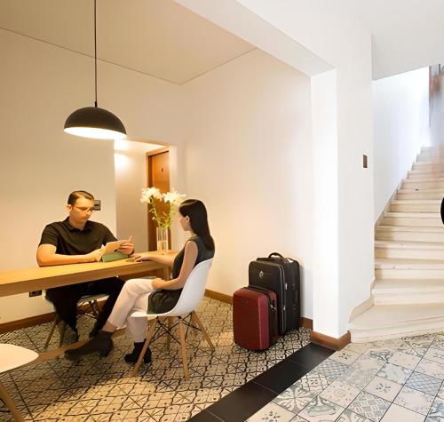 a man and woman sitting at a table with luggage at Hotel Boutique Casa Noble in Santiago