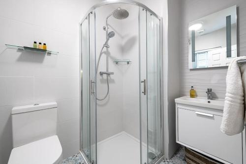 a white bathroom with a shower and a sink at Naughtons Villa in Killarney