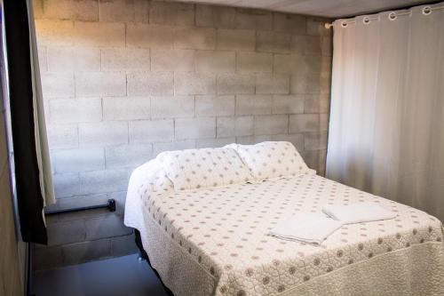 Cama en habitación con pared en Loft com vista para mata!, en Foz do Iguaçu