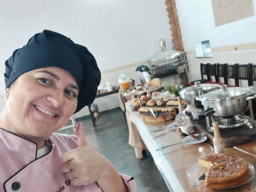 een vrouw die een duim opsteekt voor een tafel vol eten bij Recanto Varandas Guararema in Guararema