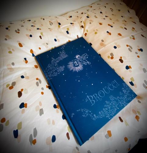 a blue book sitting on a bed with flowers at Maringotka Za Trnkou in Točník