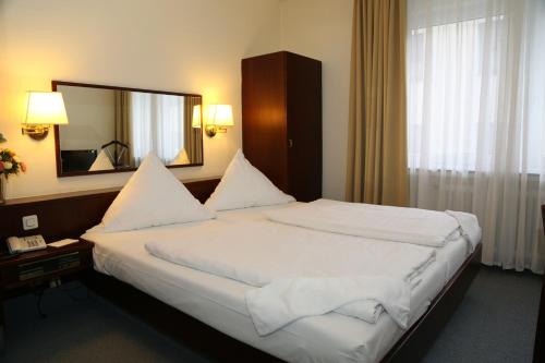 ein Schlafzimmer mit einem großen Bett und einem großen Spiegel in der Unterkunft Hotel Löhndorf in Bonn