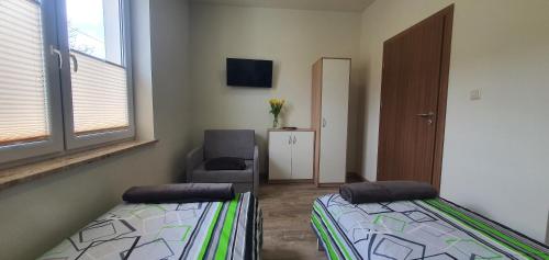 a room with two beds and a chair and a window at Zajazd Stronie in Stronie Śląskie