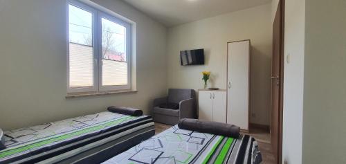 a bedroom with two beds and a chair and a window at Zajazd Stronie in Stronie Śląskie