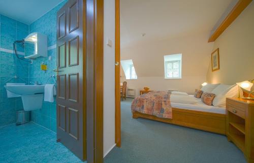 a bathroom with a bed and a sink in a room at Hotel Praha in Hřensko