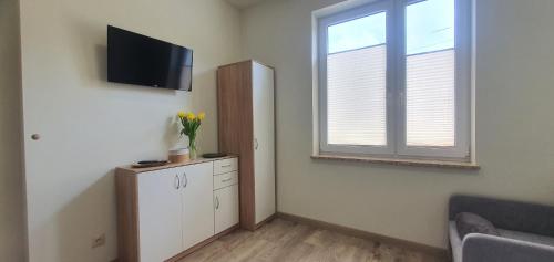 a living room with a tv and a cabinet and a window at Zajazd Stronie in Stronie Śląskie