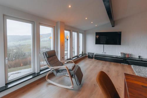 a living room with a chair and a flat screen tv at RhönKristall modernes Terrassenhaus mit Weitblick in Bischofsheim an der Rhön