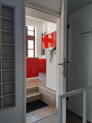 a door leading into a kitchen with red cabinets at Het Maelslot (Mechelen) in Mechelen