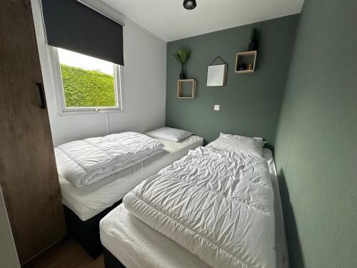 two twin beds in a room with a window at Chalet 582 op Recreatiepark de Wielen in Sint Maarten