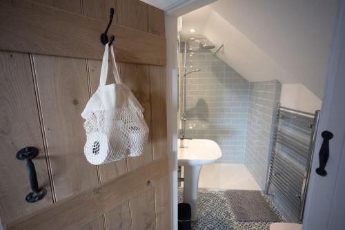 un bagno con lavandino e borsa appesa a una porta di Ty Carreg cottage, Bwlch, Brecon a Brecon