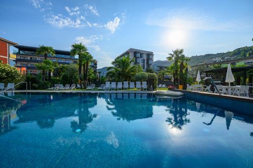 ein großer Pool mit Stühlen, Bäumen und Gebäuden in der Unterkunft Hotel Riviera in Riva del Garda