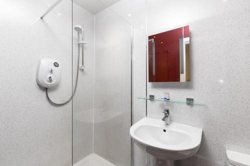 baño blanco con ducha y lavamanos en Royal Discovery, en Whitby