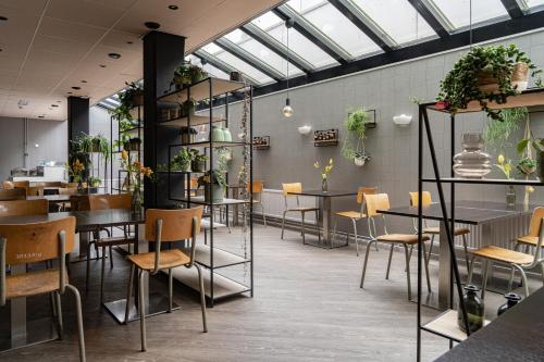 een restaurant met tafels, stoelen en planten bij Hotel de Duif Lisse - Schiphol in Lisse