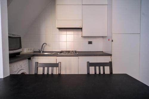 a kitchen with white cabinets and a sink and two chairs at Embarcadero with New Powerful WiFi in Camogli