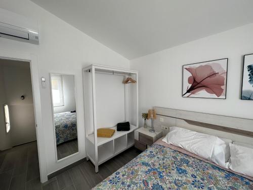 Habitación blanca con cama y espejo en DUPLEX La OLMA en Guadarrama