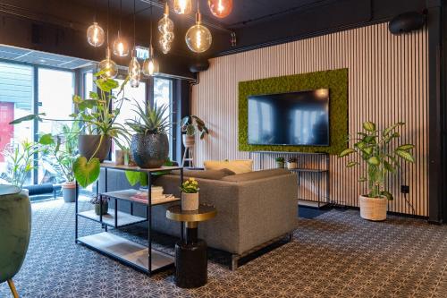 een woonkamer met een bank en een tv en planten bij Hotel de Duif Lisse - Schiphol in Lisse