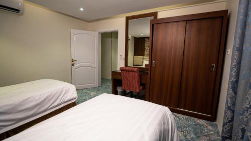 a bedroom with two beds and a desk and a closet at فندق إطلالة الحديقة in Tabuk