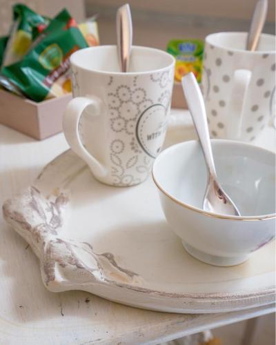 a table with two cups and a plate with two spoons at Domo 'e sa rosa in Bosa