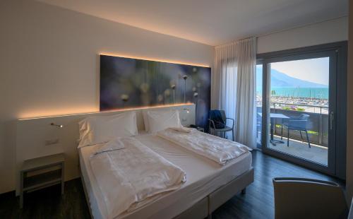 een slaapkamer met een groot bed en een groot raam bij Hotel Riviera in Riva del Garda