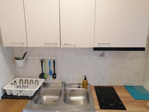 a kitchen with a stainless steel sink and white cabinets at Apartment Layla - Intermezzo with sea view in center of Rabac in Rabac