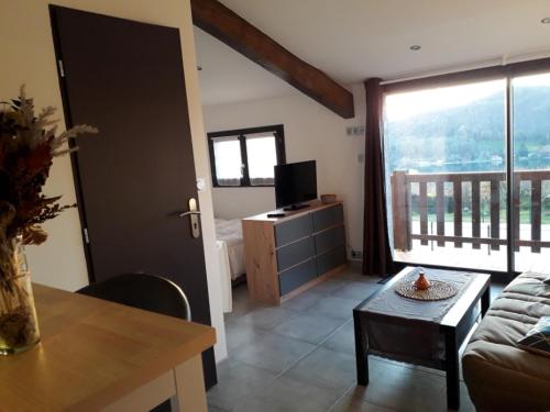 un salon avec un canapé et une télévision dans l'établissement Entre lac et montagne, à Bilieu
