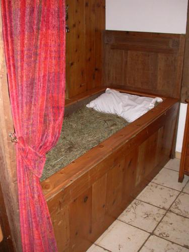 a wooden bed with hay in a room with a curtain at Olimpia Hotel in Bormio