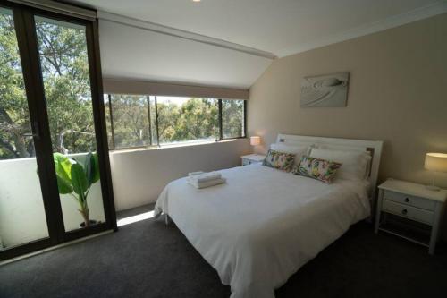 a bedroom with a white bed and a large window at Tranquil Escape - Koala Hotspot - 2 Bed 2 Bath Apt Spectacular Sea Views in Soldiers Point