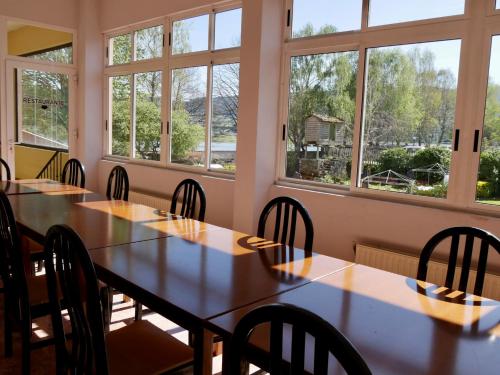 a row of tables and chairs in a room with windows at Hotel Eumesa in Puentedeume
