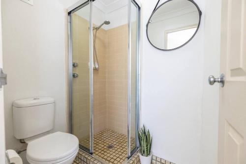 a bathroom with a shower with a toilet and a mirror at Tranquil Escape - Koala Hotspot - 2 Bed 2 Bath Apt Spectacular Sea Views in Soldiers Point