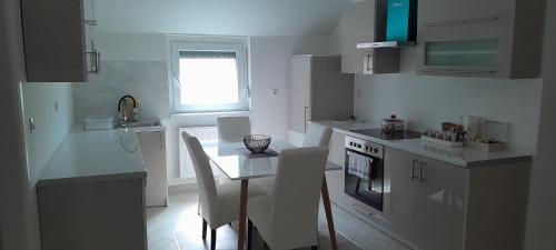 a kitchen with white cabinets and a table and chairs at Apartman XXL in Brčko