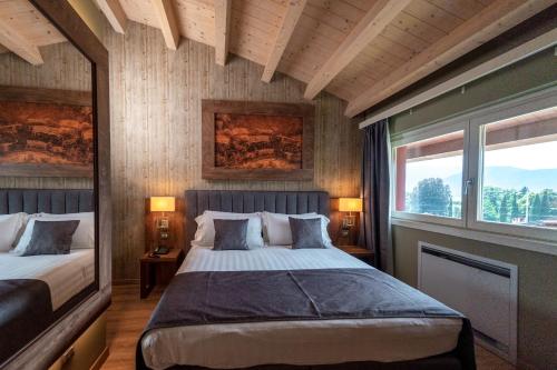 a bedroom with two beds and two windows at Lake Hotel La Pieve in Pisogne