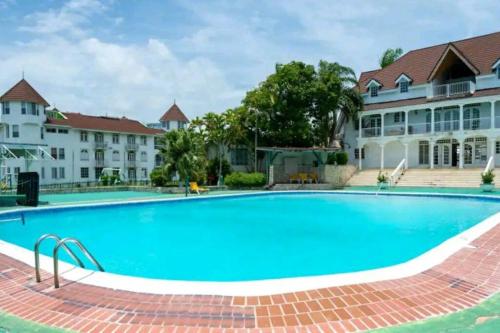 a large swimming pool in front of a building at Cozy Apartment w/Ocean View, Pool & Beach Access in Montego Bay