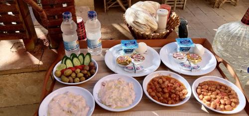 einen Tisch mit Teller mit Lebensmitteln und Wasserflaschen in der Unterkunft Panta Lodge Siwa بنتا لودج سيوة in Siwa